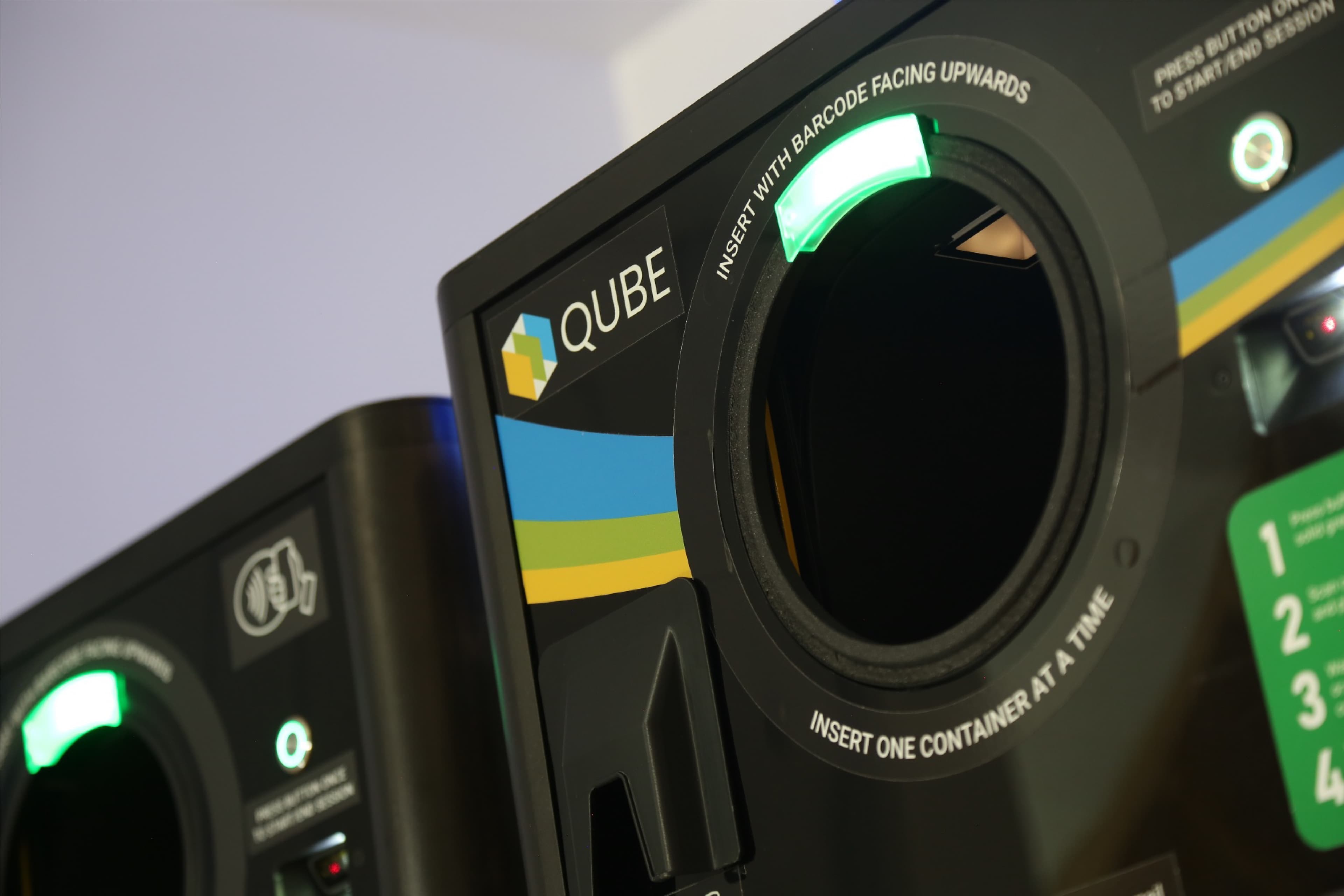 Two TrovrQUBE machines side by side, lit insertion apertures and QUBE wordmark in view