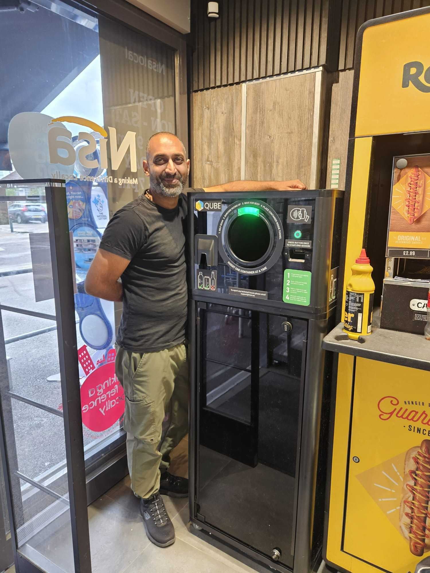 Kaual Patel standing beside a TrovrQUBE installed in his Catford convenience store.